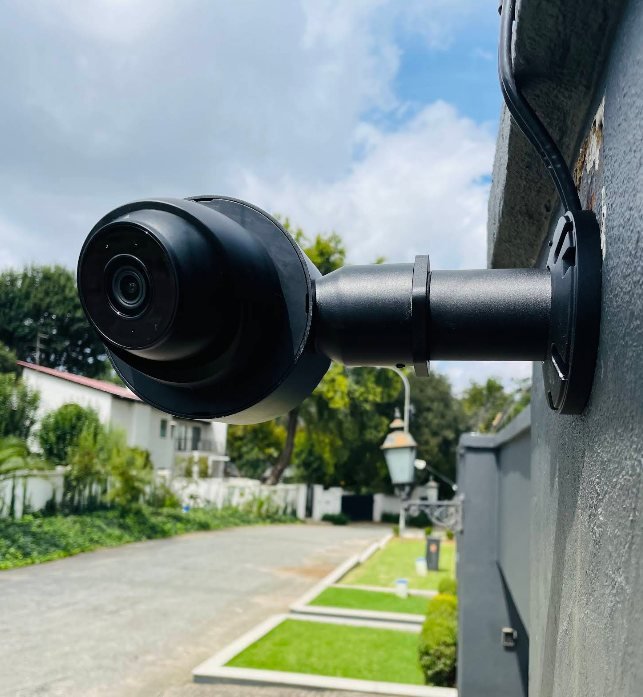 An outdoor CCTV camera mounted on a wall overlooking a residential driveway