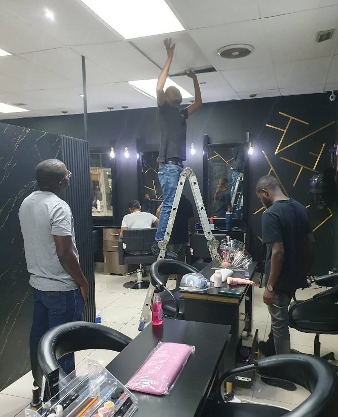 GreyX technicians installing ceiling equipment inside a working hair salon