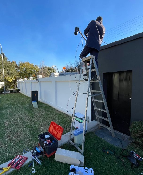 A GreyX technician on a ladder installing equipment on an exterior wall
