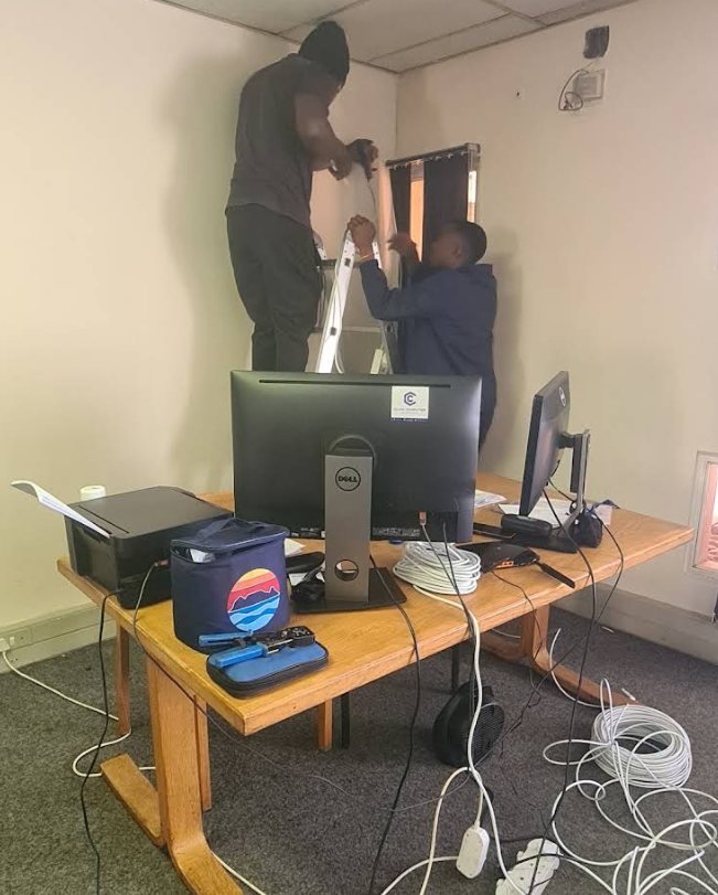 Two GreyX technicians setting up a desktop workstation and monitor in an office