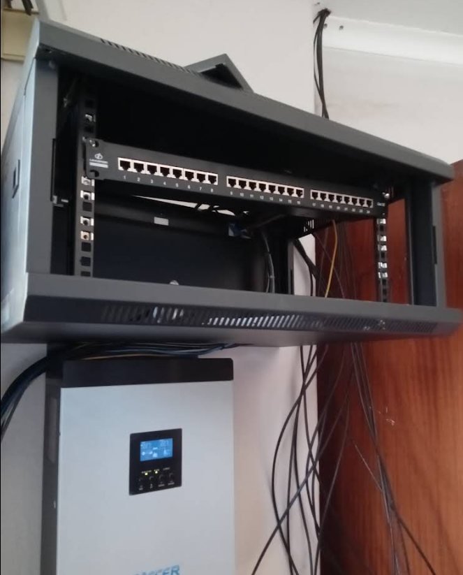 An open network rack alongside a wall-mounted inverter and power panel